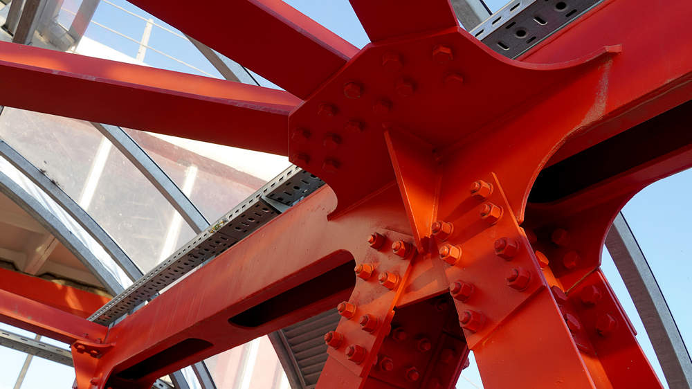 Red iron beams bolted on Angular connection of several iron beams in one place close up